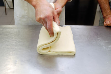Piegatura pasta sfoglia fatta in casa. Mani chef al lavoro, preparazione dolce.