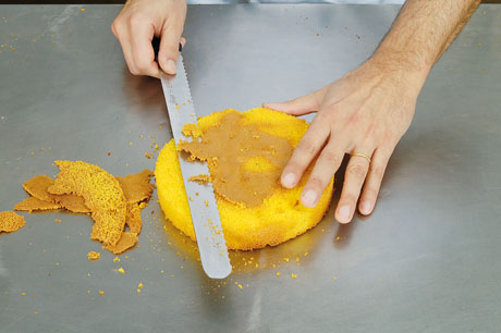 Preparazione torta: cuoco taglia pan di Spagna con coltello. Ricetta dolce.
