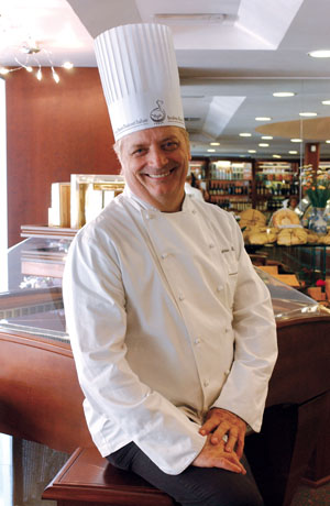 Igino Massari, famoso pasticcere italiano, indossa la divisa da chef e sorride.