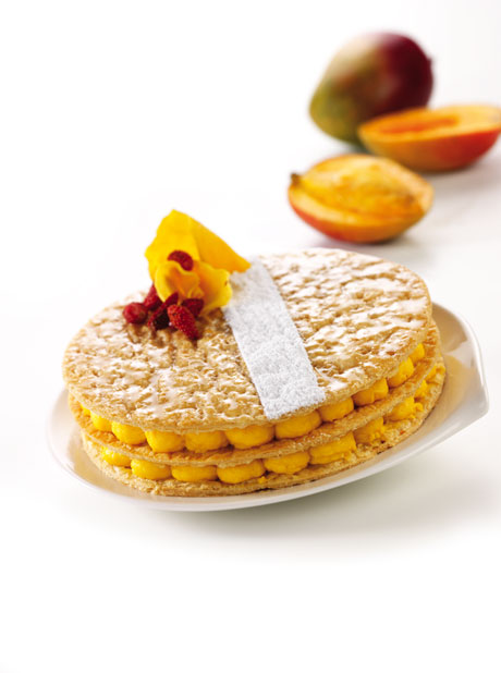 Millefoglie esotico con mango, crema e decorazioni floreali. Dolce squisito e invitante.