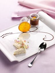 Semifreddo all'amaretto su piatto bianco con arancia, crema al cioccolato e cucchiaio. Dessert elegante.