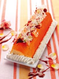 Tronchetto gelato arancione decorato con panna e cioccolato. Dessert festivo, pasticceria creativa.