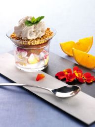 Dolce al cioccolato in tazza con panna, arancia e petali. Dessert goloso e invitante.