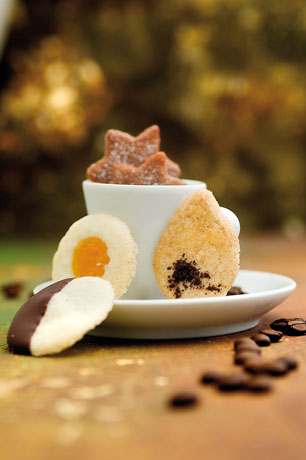 Dolcetti assortiti di pasta sablée su tazza e piattino con chicchi di caffè. Biscotti artigianali.