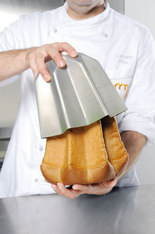 Chef pasticcere con pandoro artigianale. Stampo in metallo per dolce natalizio.