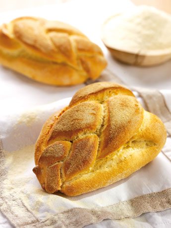 Pane treccia dorato su lino bianco. Panificazione artigianale, ricetta tradizionale. Farina in ciotola.