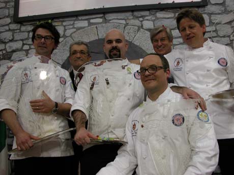 Team di chef vincitori in divisa bianca. Gruppo di cuochi sorridenti celebrano il successo culinario.