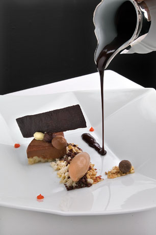 Dessert al cioccolato. Salsa versata su torta, gelato e crumble. Ristorazione di lusso.