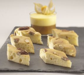 Focaccia dolce a fette con noci pecan e dessert in vetro. Dolci italiani artigianali su ardesia.