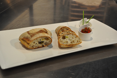 Pane artigianale affettato con salse su piatto bianco. Antipasto gourmet, cucina italiana.