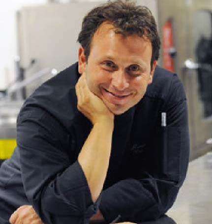 Chef sorridente in divisa nera. Cucina italiana, ristorazione di alta qualità.