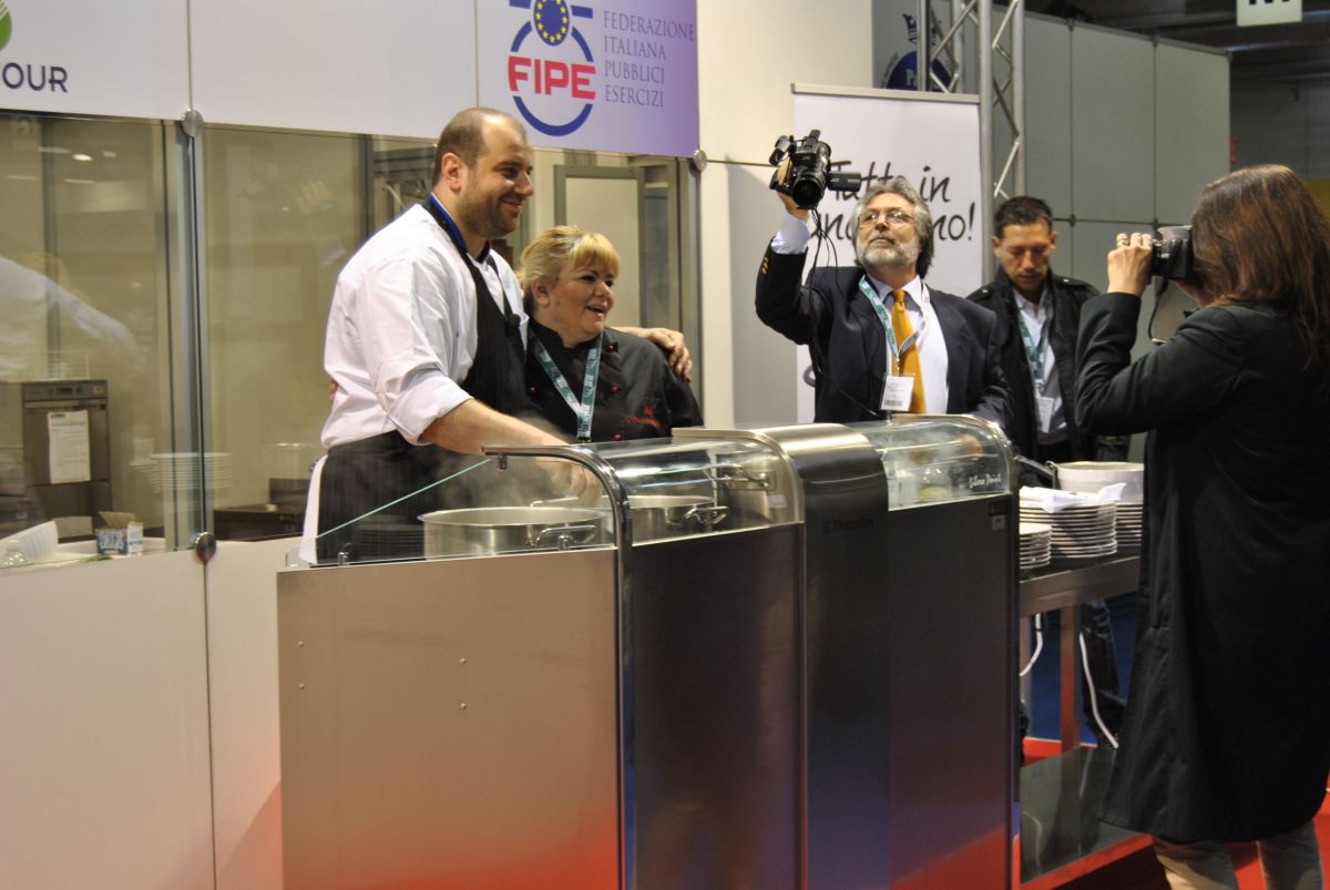 Chef Fabio Romani in fiera. Cuochi al lavoro, evento culinario, giornalisti e fotografi. Cucina italiana.