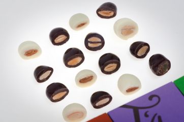 Cioccolatini dragées: mandorle ricoperte di cioccolato bianco e fondente. Dolciumi artigianali, snack golosi.
