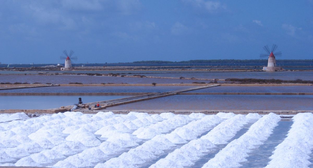 Saline di Trapani, Sicilia. Cumuli di sale, mulini a vento e vasche d'acqua. Paesaggio suggestivo.