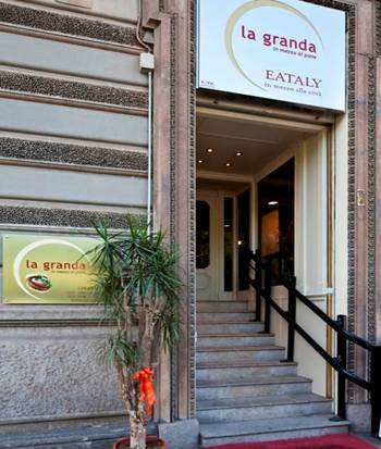 Ingresso del ristorante La Granda Eataly. Scala d'accesso, insegne luminose. Cucina tipica italiana.