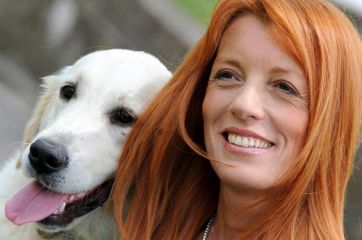 Donna sorridente con Golden Retriever. Amicizia tra cane e padrona. Capelli rossi.