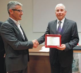 Premiazione Sig. Genesio: stretta di mano e consegna targa. Evento, riconoscimento, successo.