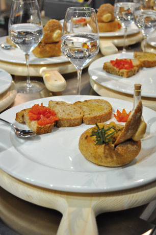 Tavola imbandita con pane, pomodori e bicchieri d'acqua. Cucina salutistica italiana, cibo sano e gustoso.