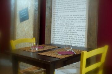 Tavolo ristorante con sedie gialle, tovagliette e bicchieri. Arredamento interno.