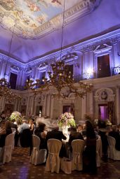 Sala ricevimenti lussuosa con affreschi, lampadari e tavoli imbanditi per evento.