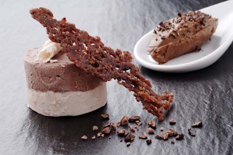 Dolce al cioccolato: tortino a strati, cialda croccante e mousse su cucchiaio. Dessert elegante.
