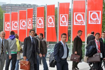 Fiera Anuga: persone e bandiere rosse con logo Anuga. Evento internazionale alimentare e bevande a Colonia, Germania.