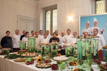 Team di pasticceri con dolci artigianali. Tavolo imbandito con torte e decorazioni floreali. Pasticceria italiana.