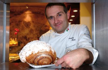 Chef italiano con brioche gigante. Pasticceria artigianale, dolce da forno.