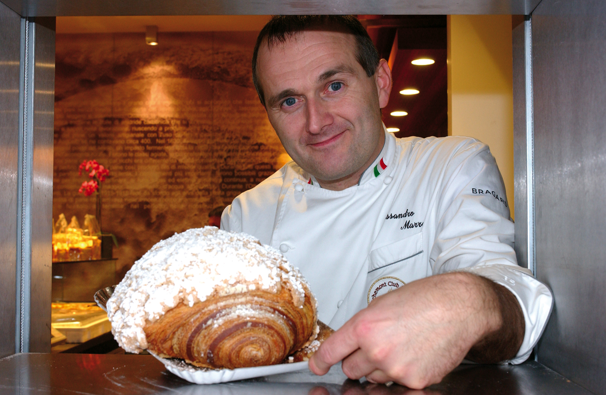 Chef italiano con brioche gigante. Pasticceria artigianale, dolce da forno.