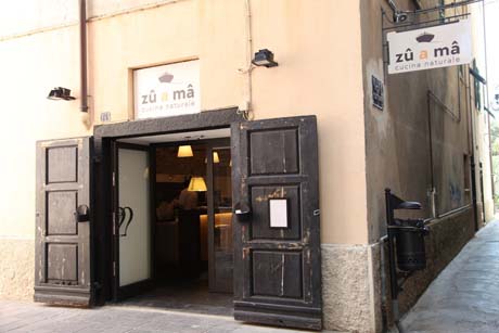 Ingresso del ristorante Zù a Mà, cucina naturale. Porta in legno aperta. Gastronomia, ristorazione.