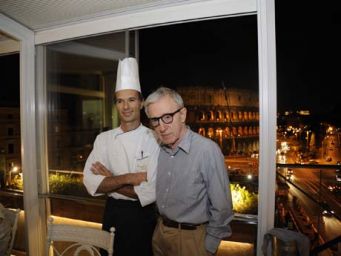 Woody Allen con chef a Roma, Colosseo illuminato sullo sfondo. Cena gourmet, celebrità a Roma.