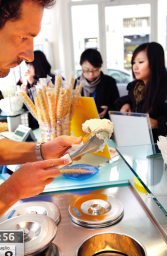 Gelateria artigianale: gelataio serve gelato su cono. Clienti in attesa. Delizie estive, gusto italiano.