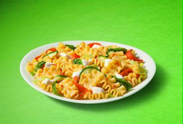 Piatto di mafalde corte con verdure fresche. Pasta italiana, zucchine, peperoni rossi e basilico. Ricetta vegetariana.