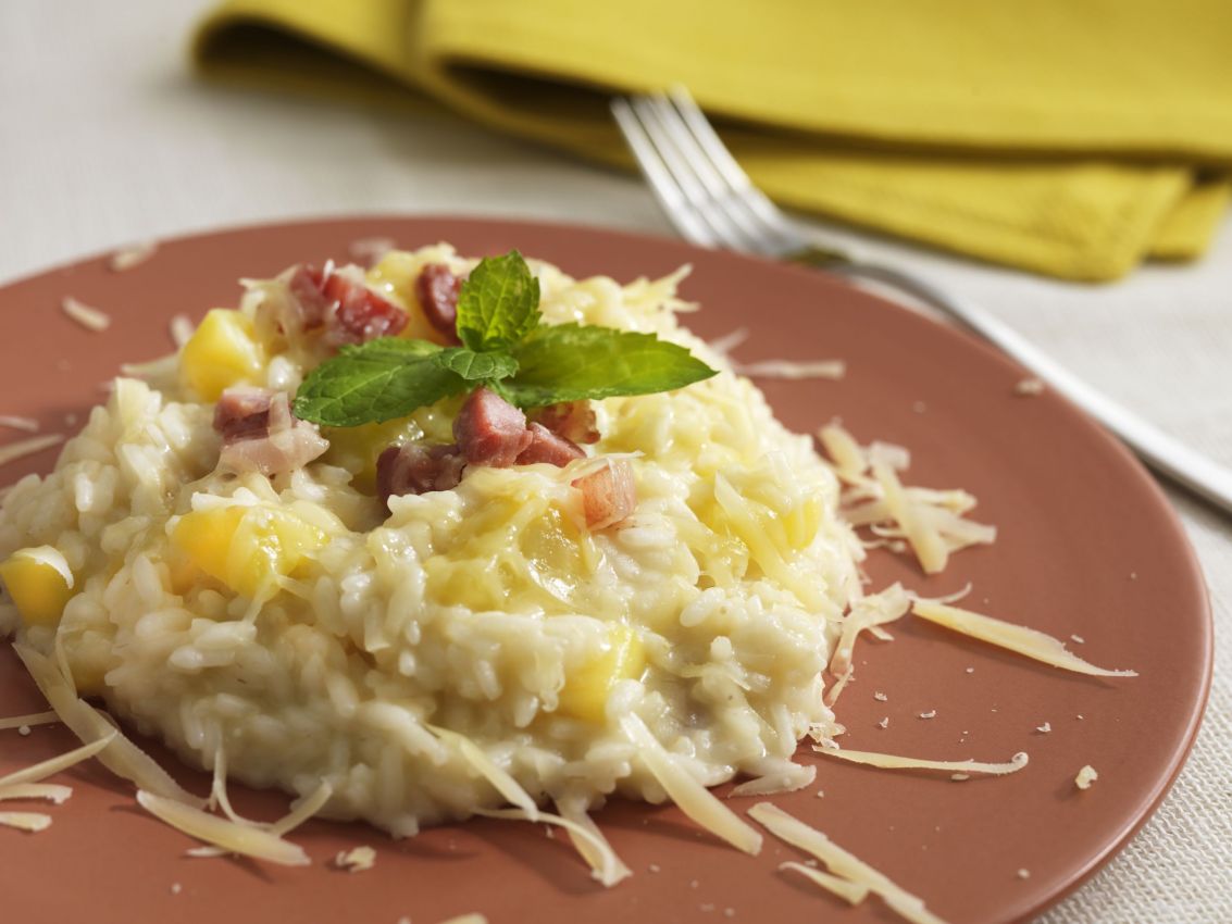 Risotto allo Sbrinz con pere, zafferano e pancetta. Piatto gourmet della cucina italiana.