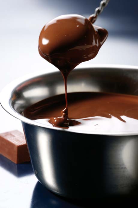 Cioccolato fuso in ciotola. Cucchiaio con cioccolato che cola. Dolce al cioccolato, dessert goloso.