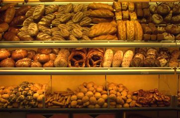 Assortimento di pane fresco in panetteria. Varietà di pane artigianale, panini e prodotti da forno.