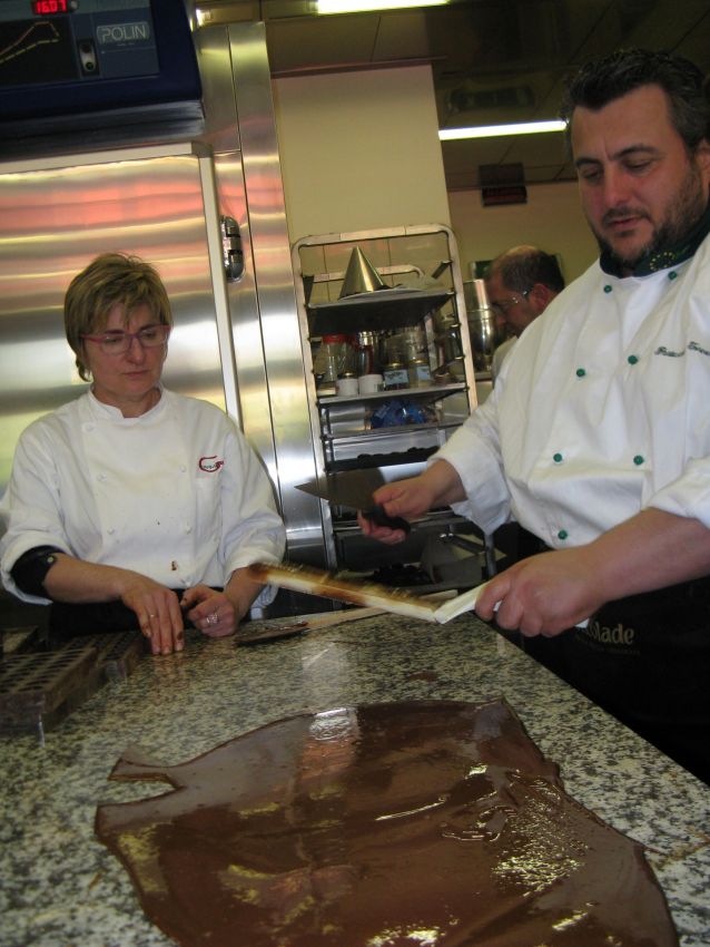 Chef al lavoro con cioccolato fuso. Corso di cioccolateria, preparazione dolci.