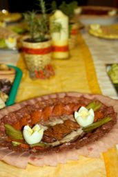 Assortimento di salumi misti su piatto ovale. Prosciutto, salame, uova sode e cetriolini. Tavola imbandita.