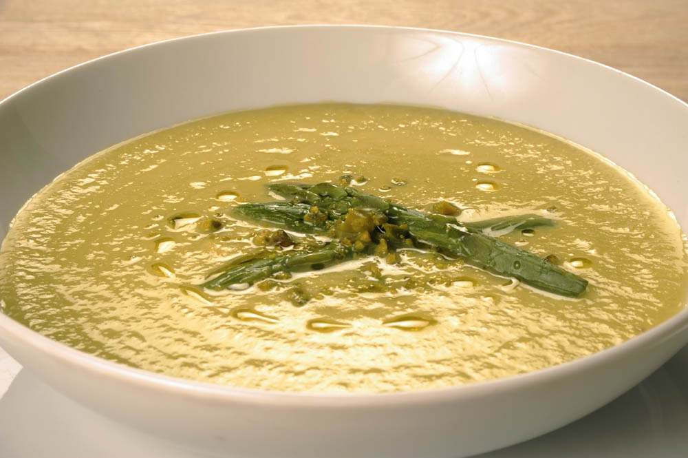 Crema di asparagi e pistacchi in ciotola bianca. Zuppa primaverile, piatto vegetariano.