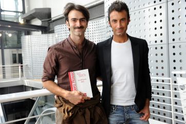 Due uomini sorridenti con libro Gambero Rosso. Moda uomo, stile italiano.