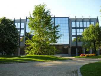 Architettura moderna con facciata a vetri, alberi verdi e prato curato. Design urbano, esterni di edifici.