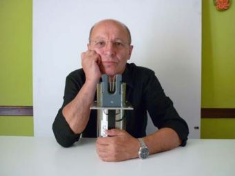 Uomo con occhiali e orologio presenta strumento di precisione. Prototipo, innovazione tecnologica.