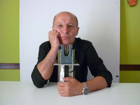 Uomo con occhiali e orologio presenta strumento di precisione. Prototipo, innovazione tecnologica.