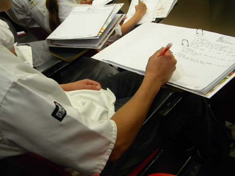 Studente scrive appunti su quaderno ad anelli. Aula scolastica, studio, apprendimento.
