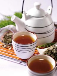 Tè caldo in tazza con teiera bianca. Bevanda rilassante, tisana alle erbe.