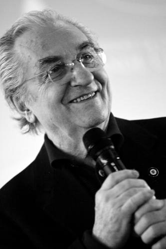 Uomo anziano sorridente con microfono. Ritratto in bianco e nero, oratore, conferenza.