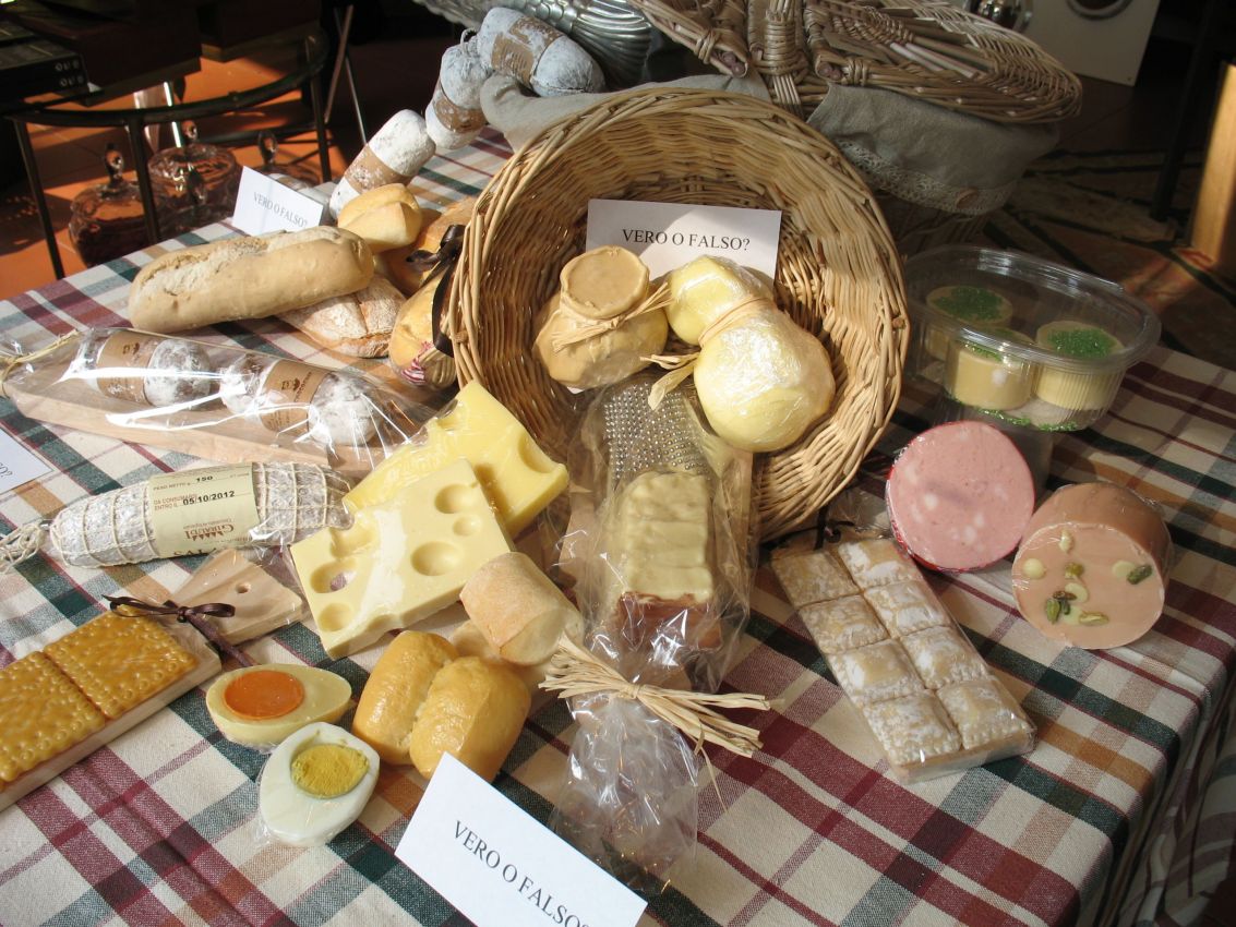 Assortimento di prodotti alimentari artigianali: formaggi, salumi, pane e dolci confezionati su tovaglia a quadri. Vero o falso?.
