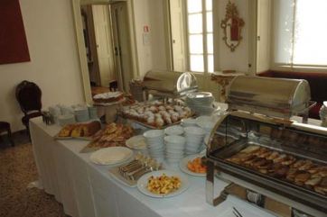 Buffet colazione in sala elegante. Dolci, torte, frutta e scaldavivande in acciaio. Catering per eventi.
