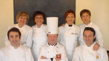 Foto di gruppo chef italiani. Team di cucina con toque, giacche bianche. Ristorazione di alta qualità.