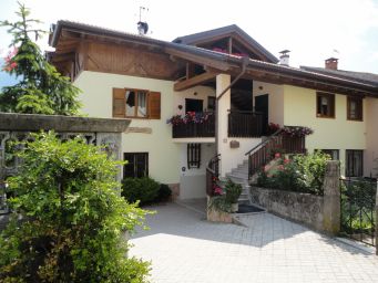 Agriturismo tipico. Casa vacanze con balcone fiorito, scala esterna e dettagli in legno. Ospitalità rurale.